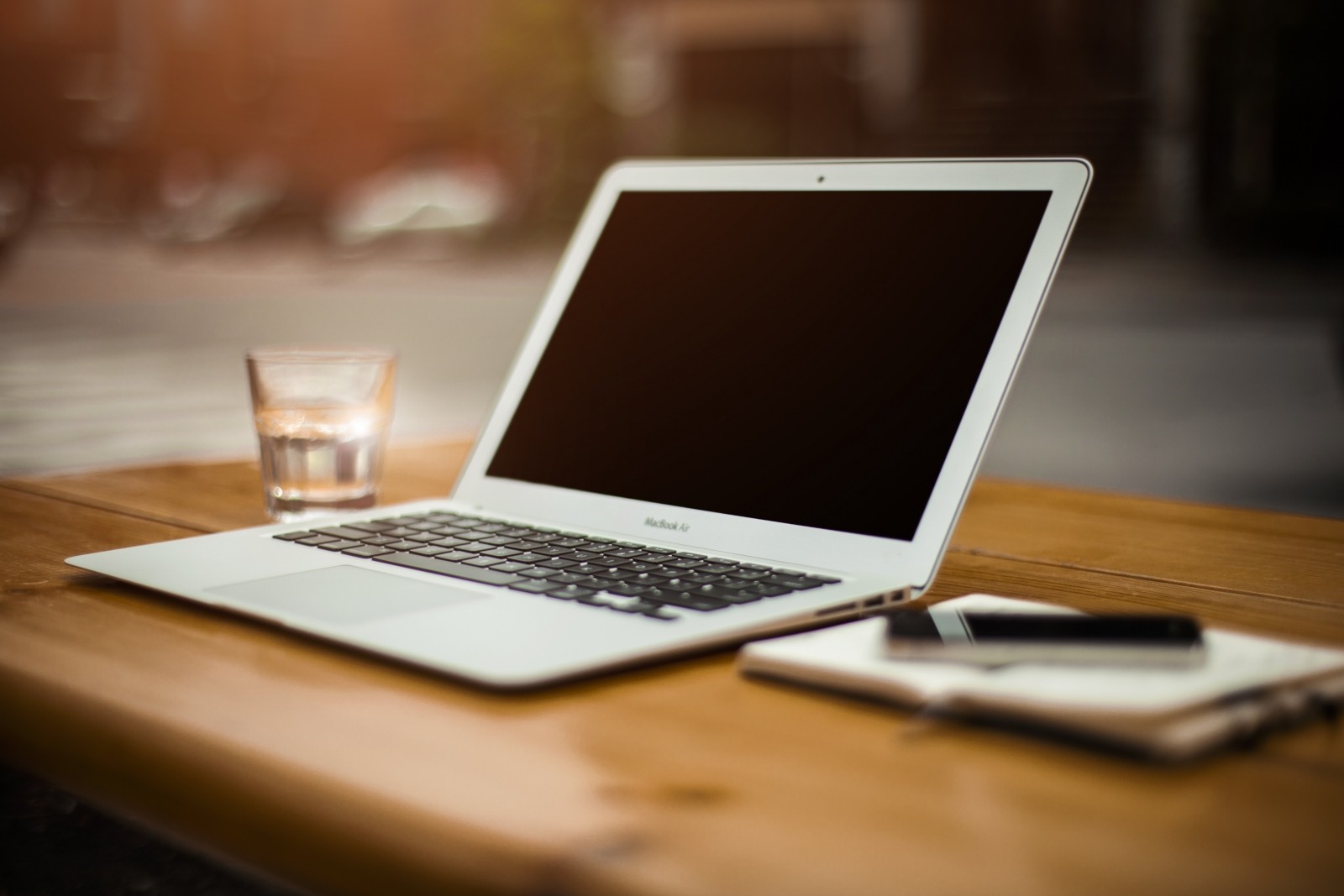 laptop-mobile-phone-and-water-glass-on-wooden-table